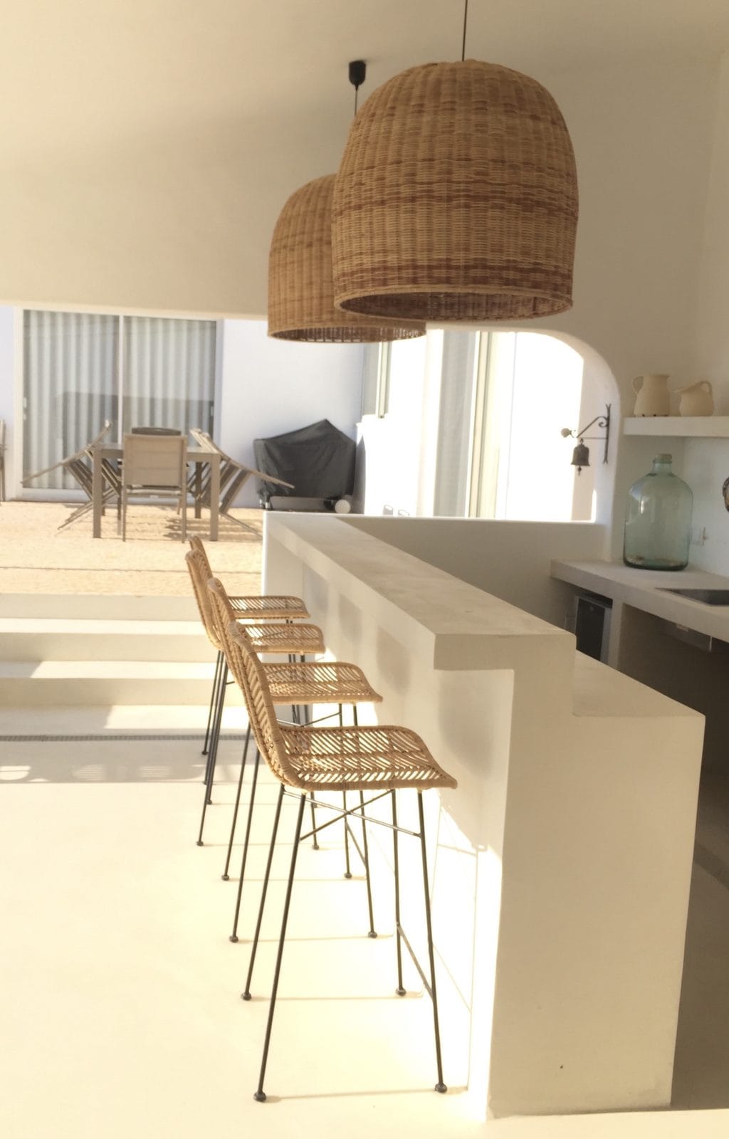 Península de cozinha em microcimento branco com bancos altos e pavimento contínuo — KCBerry